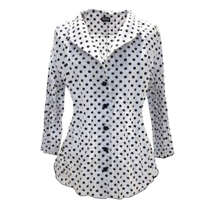 The blouse is called Clarendon Dot White / Black and shows a shawl collar with 3/4 sleeves. The body of the blouse is white with block dots. Buttons are black.
